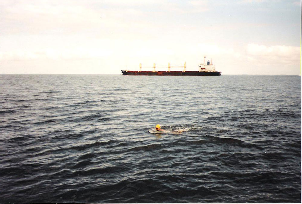 Kirsten Seidel swimming in open water with a cargo ship in the background.