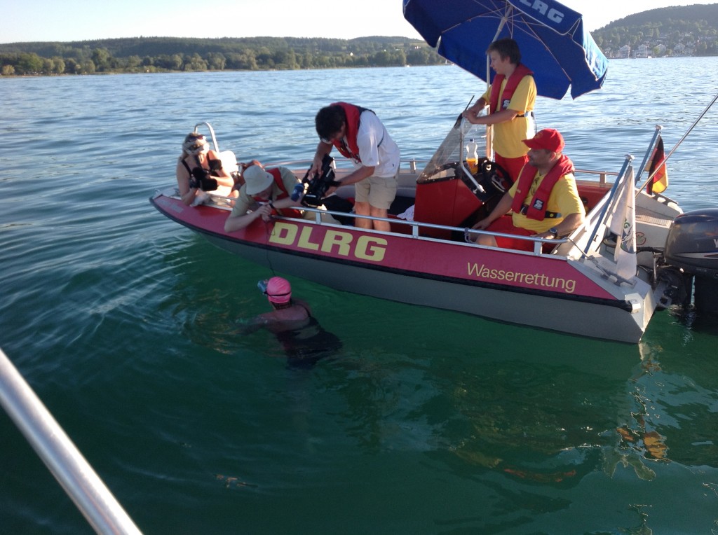 Kirsten Seidel in the water alongside a DLRG support boat on Lake Constance.